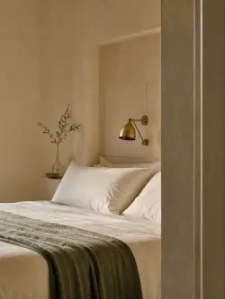 L’applique in ottone e il ramo d’olivo sopra il letto